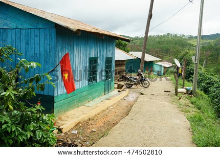 NHA TRANG, VIETNAM - JUNE 23, 2016: Small wooden house with flag in a village of tropical jungle. In the yard there is a motorcycle and nobody's around