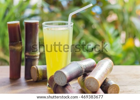 Sugarcane fresh juice with piece of sugarcane on wooden background. Closeup image / Selective focus