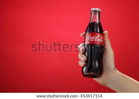Kuala Lumpur,Malaysia 11th July 2016, Hand hold a bottle Coca-Cola on red background. Coca Cola drinks are produced and manufactured by The Coca-Cola Company.