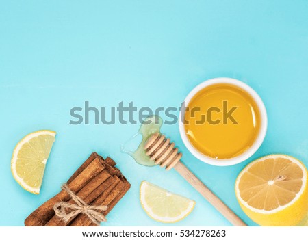 Lemon, honey and cinnamon sticks on turquoise blue background with copy space. Top view or flat lay.