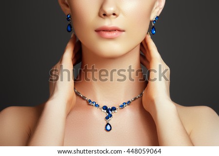 Eegant fashionable woman with jewelry. Beautiful woman with a sapphire necklace. Beauty young model with a diamond pendant on a gray background. Jewellery and accessories