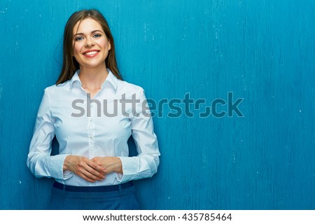 Smiling young business woman portrait on blue wall background. White shirt.