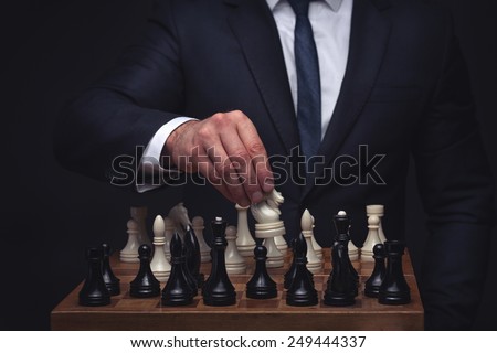 business man playing chess on dark studio background