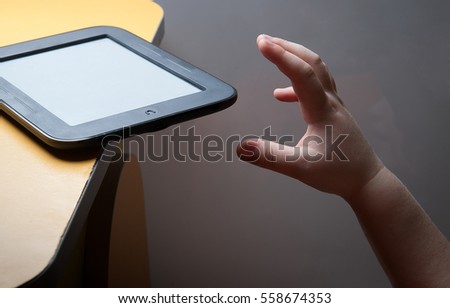 Media addiction. child is going throw a tablet on the floor. child's hand reaches smartphone. mobile phone is dangerous lies on edge. tablet or eBook carelessly left. cell phone dangerously resting.