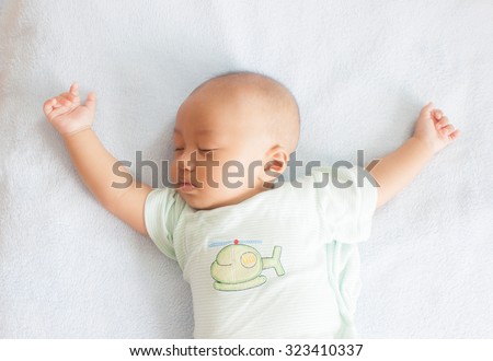 Sleeping baby on back on white bed