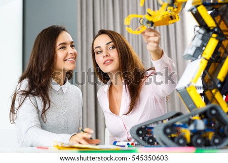New teammate. Two beautiful female colleagues working on a robotics development project together beautiful young businesswoman holding a hand of the robot woman touching robot