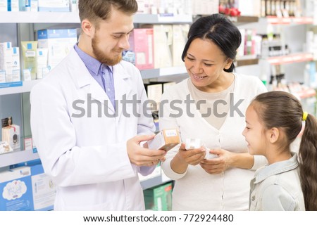 Male pharmacist helping his customers mother and little daughter with prescripted medications at the local drugstore assistance salesperson medical industry buyers purchase consumers offer
