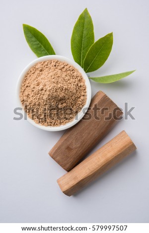 Chandan or sandalwood powder with traditional mortar, sandalwood sticks, perfume or oil and green leaves. selective focus