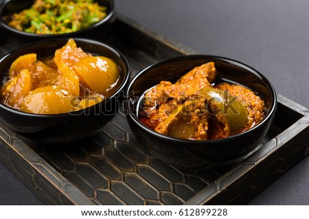 Group photograph of indian pickles like mango pickle , lemon pickle and green chilli pickle, sarved in white ceramic bowl, selective focus