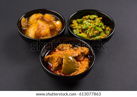 Group photograph of indian pickles like mango pickle , lemon pickle and green chilli pickle, sarved in ceramic bowls, selective focus