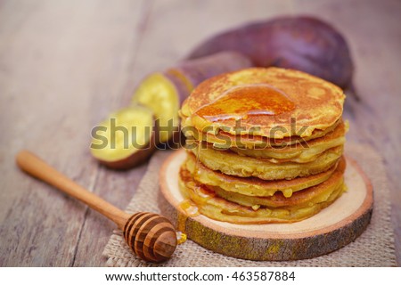 Sweet potato pancakes with honey on wooden plate.