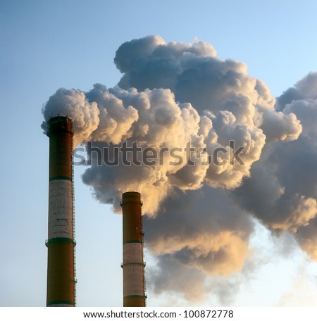 Air pollution by smoke coming out of two factory chimneys.
