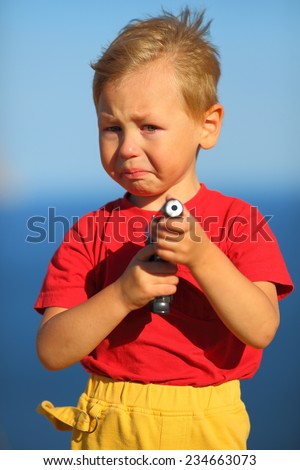 crying  boy with a gun on the coast