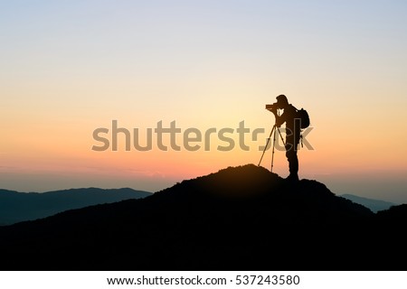 silhouette of photographer on top of mountain at sunset background