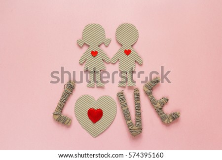 Cardboard silhouettes girl and boy with hearts and the word love on a pink background. Valentine's Day background. Top view.