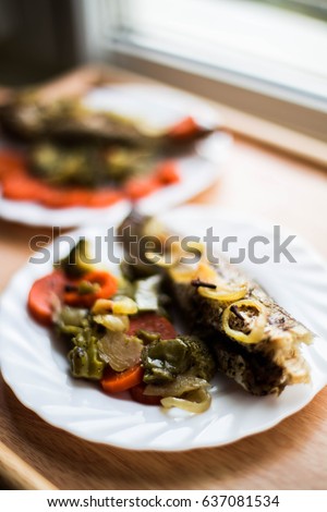 Baked roasted fried fish with baked, baked, gifted vegetables on a wooden table