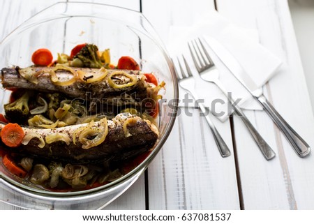 Baked roasted fried fish with baked, baked, gifted vegetables on a white wooden table