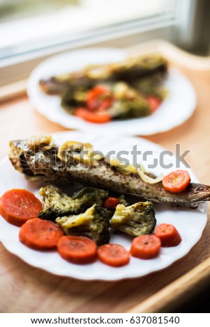 Baked roasted fried fish with baked, baked, gifted vegetables on a wooden table