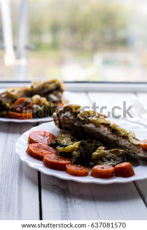Baked roasted fried fish with baked, baked, gifted vegetables on a white wooden table