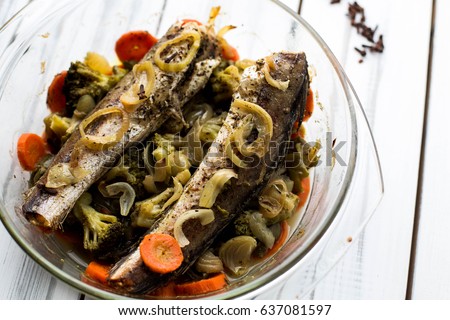 Baked roasted fried fish with baked, baked, gifted vegetables on a white wooden table