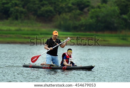 The Farther and son Playing Stand up paddle boards (SUP) offer a fun, relaxing way to play on the water, Cam Son Lake, Bac Giang, Viet Nam 2016