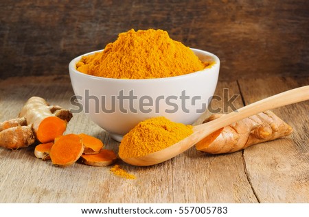 Turmeric roots with turmeric powder on wooden background