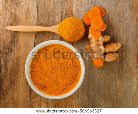 Turmeric roots with turmeric powder on wooden background,top view