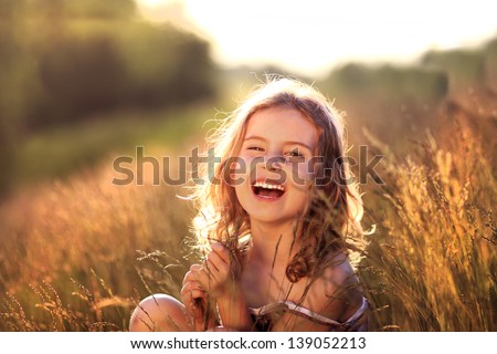 Adorable little girl laughing in a meadow - happy girl