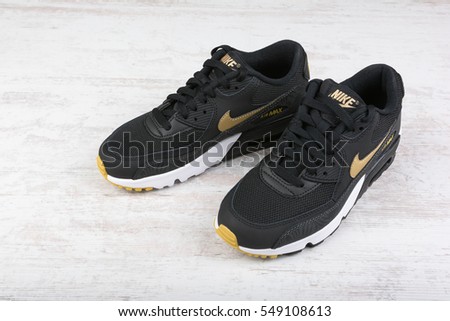BURGAS, BULGARIA - DECEMBER 29, 2016: Nike Air MAX women's shoes - sneakers in black, on white wooden background. Nike is a global sports clothes and running shoes retailer.
