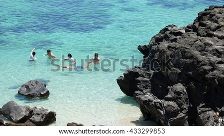 LYSON ISLAND, QUANG NGAI PROVINCE, VIETNAM - JUNE 2016: Unidentified people are swimming on the blue sea of Ly Son island, besides the volcanic rocks. Ly Son is an ancient volcanic island.