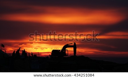 LY SON ISLAND, VIETNAM - JUNE 2016 : Beautiful sunset over boats on the sea of Ly Son island, Quang Ngai province, Vietnam. Flag and crane waving in the red sky. Revolution abstract. Sihouette.