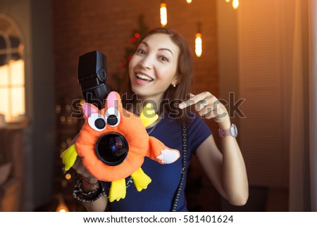 Woman photographer with a children's toy on the camera lens to attract the child's attention