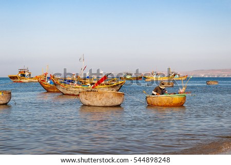 Fishing village, market and colorful traditional fishing boats near Mui Ne, Binh Thuan, Vietnam. Early morning, fishermen float to the coast with a catch.