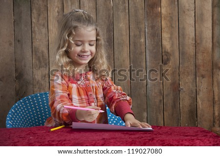 little girl writing a letter , wooden background