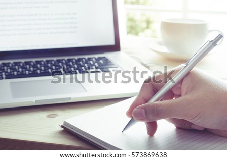 Businessman writing on notebook with laptop.Inspiration moment,working or coffee break in morning