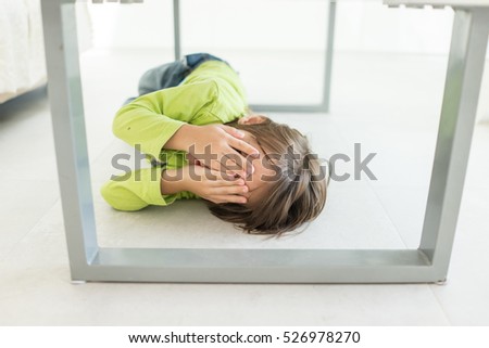 Kid covering his face under the table at home