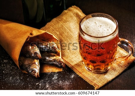 dried fish and vintage glass of beer on a black background