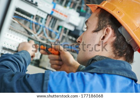 Young adult electrician builder engineer screwing equipment in fuse box
