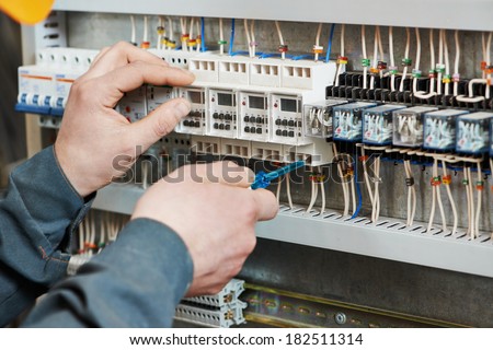 Hands of electrician with screwdriver tighten up switching electric actuator equipment in fuse box