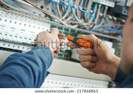 Hands of electrician with screwdriver tighten up switching electric actuator equipment in fuse box