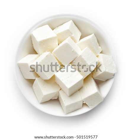Bowl of diced soft cheese isolated on white background, top view