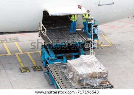Aircraft handling before flight. Technician staff load the cargo pallets in the airplane cargo compartment.