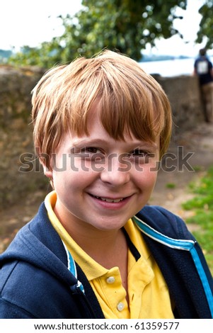 cute smiling young boy sitting on a bench in a garden