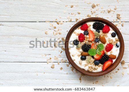 bowl of greek yogurt with granola, oats, berries and nuts for healthy breakfast. top view