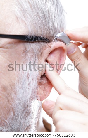 hearing test aid inserting ear closeup senior man shutterstock