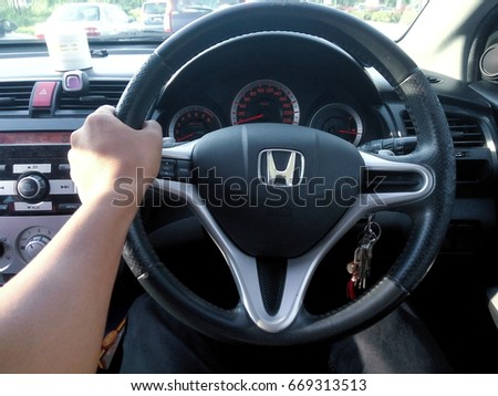 KUALA LUMPUR, January 13, 2016 : View of a hand holding HONDA steering and meter. Focus on HONDA logo. A crop close up steering wheels