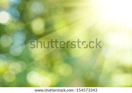 Natural outdoors bokeh background in green and yellow tones with sun rays