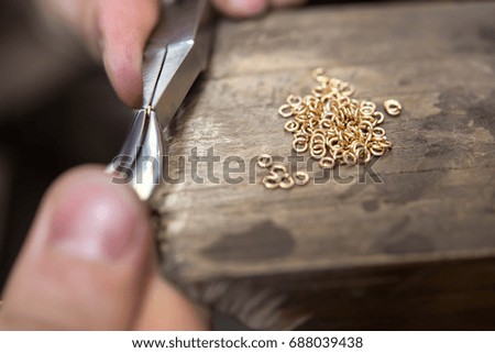 Craft jewelery making with professional tools. Gold chain repairing. Fixing one piece of chain to the others. Macro shot. A handmade jeweler process, manufacture of jewellery.