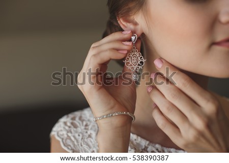 Wedding earrings on a female hand, she takes the earrings, the bride fees, morning bride, white dress, wear earrings