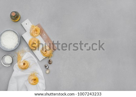 Pasta making process. Pasta dough, quail eggs, flour, olive oil, kitchen staff on a concrete grey background.